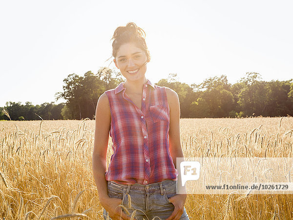 A young woman standing in a field of tall ripe corn.