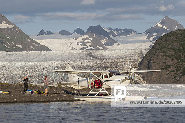 People unloading gear from a floatplane in front of Grewingk glacier in Kachemak Bay State Park  Southcentral Alaska.