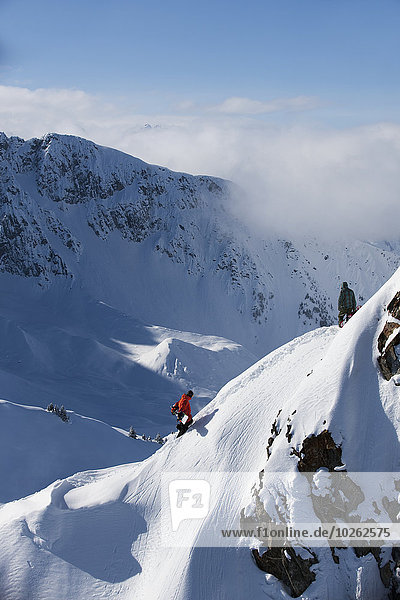 Extreme snowboarders walking a mountain ridge in the mountains above Haines  Southeast Alaska  USA