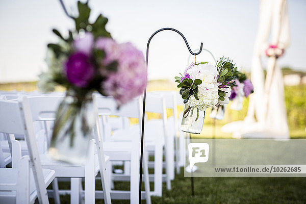 Flowers Hanging at End of Rows of Chairs at Wedding