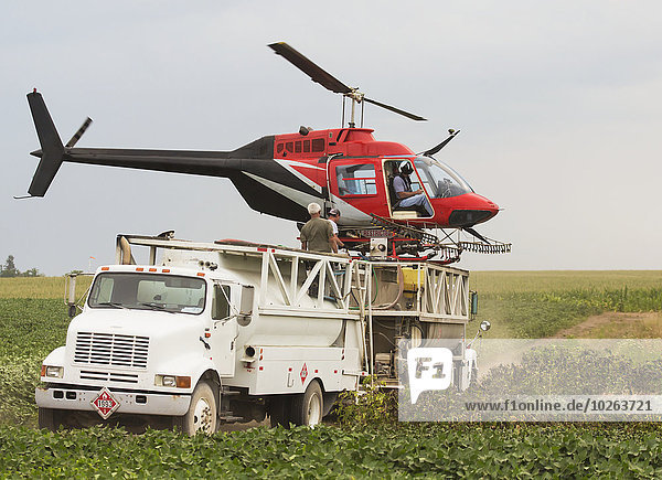 Crop dusting helicopter landed on top of tank truck refilling for another flight; Iowa  United States of America