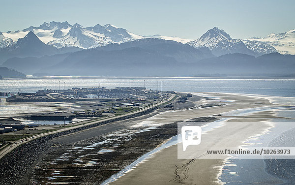 Aerial view of the Homer Spit and Kenai Mountains with horseback riders on the beach  Southcentral Alaska  Spring