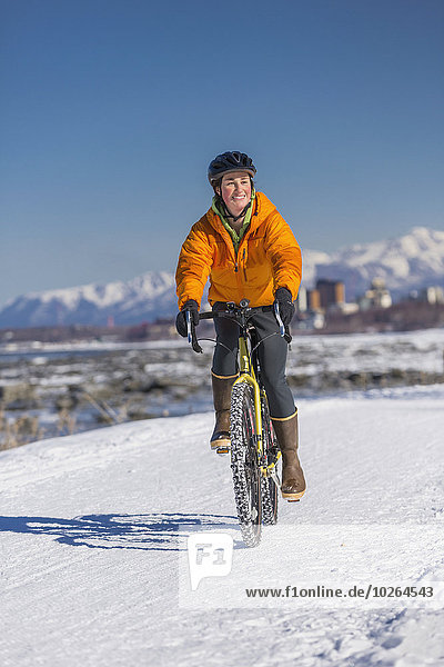 A Young Woman rides a studded tire bicycle down the Tony Knowles Coastal Trail  Anchorage  Southcentral Alaska  USA.