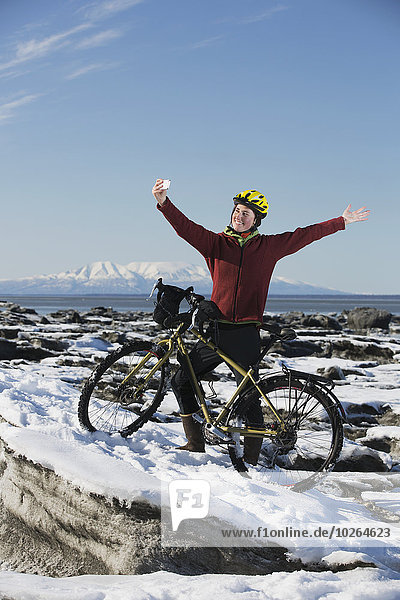 stehend junge Frau junge Frauen nehmen folgen Küste Eis vorwärts Fahrrad Rad Smartphone Stück gefroren