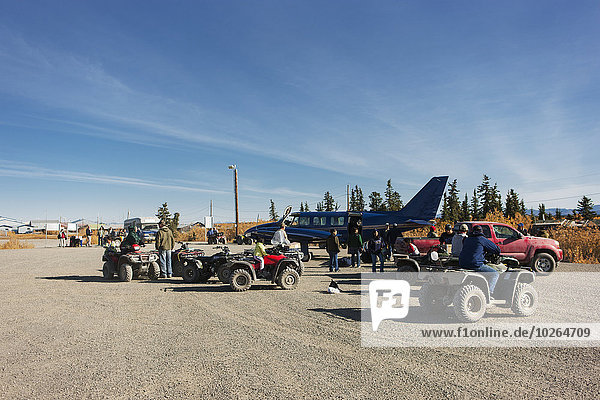 Locals with their trucks and ATVs surround an airplane on a gravel landing strip  Noatak  Arctic Alaska  Autumn  USA