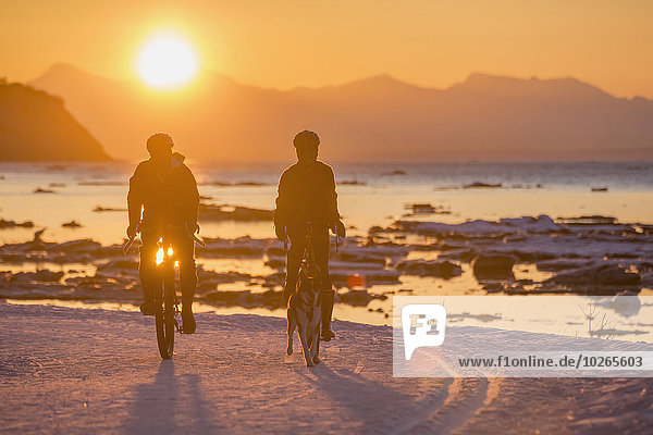Couple bicycling in winter at sunset on the Tony Knowles Coastal Trail  Cook Inlet  Southcentral Alaska