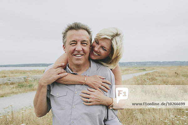 Happy senior couple embracing on a grassy beach; Coquitlam  British Columbia  Canada