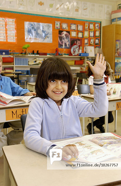Grade 2 female student raising her hand in classroom