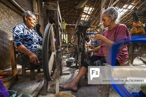 Women spinning yarn at a lurik fabric workshop in Cawas village  Klaten  Central Java  Indonesia