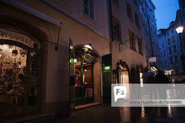 People stroll past shops in the pedestrianised streets of the old city on a rainy day; Salzburg  Austria