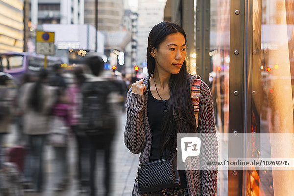 A young woman walking along the street and shops  Kowloon; Hong Kong  China