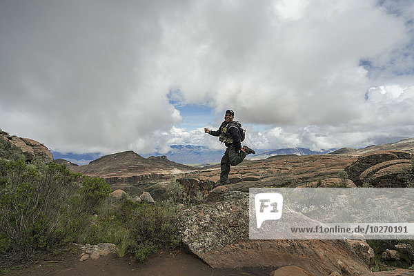 A man jumps on a rock looking out over the beautiful landscape of Toro Toro National Park; Bolivia