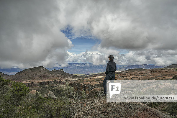 A woman stands on a rock looking out over the beautiful landscape of Toro Toro National Park; Bolivia