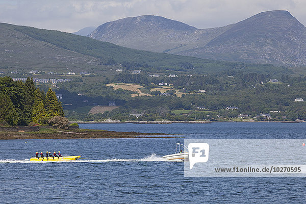 A boat pulls an inflatable banana ride in the lake; Kenmare  County Kerry  Ireland