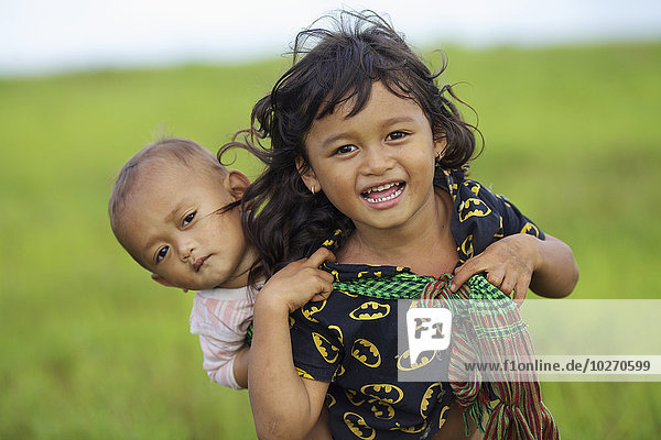 A young Bunong girl carrying her baby sister on her back; Mondulkiri  Cambodia