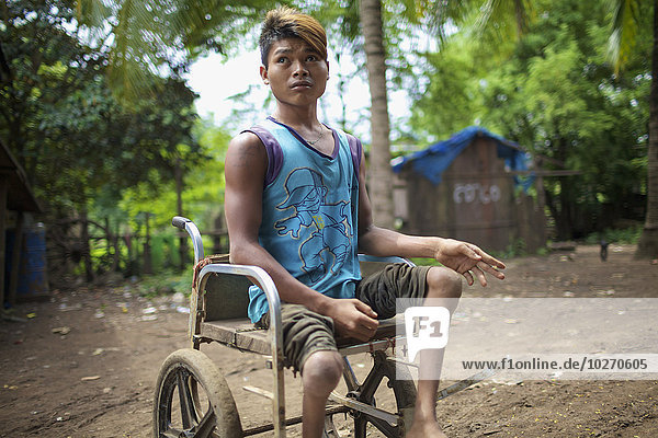 Verkrüppelter junger Mann in einem Rollstuhl; Mondulkiri  Kambodscha