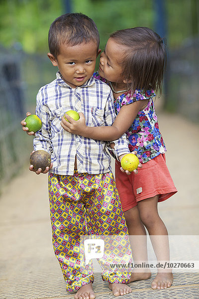 Junges Mädchen flüstert einem kleinen Jungen zu; Battambang  Kambodscha