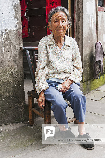 Porträt einer älteren Frau  die vor ihrem Haus in einem kleinen Dorf in der Nähe von Wuyuan sitzt; Provinz Jiangxi  China