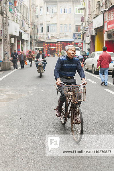 Ein älterer Mann fährt mit dem Fahrrad durch eine Straße im Stadtzentrum; Xiamen  Provinz Fujian  China