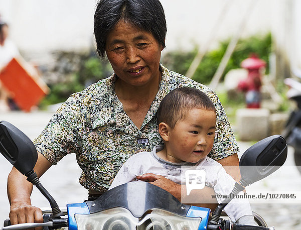 Chinese woman and boy riding a motorcycle  Hongcun  Anhui  China