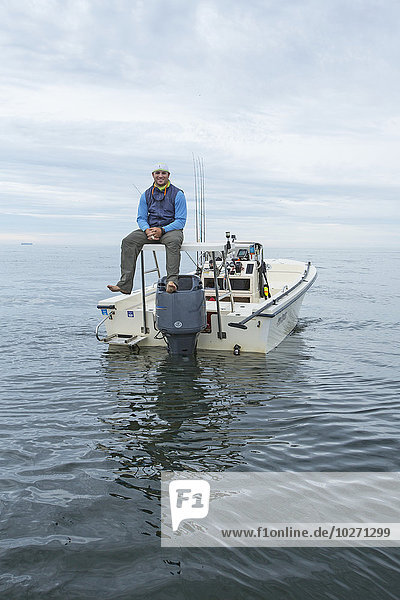 Fischer sitzt auf seinem Boot auf dem ruhigen Ozean Wasser  Boston Hafen; Boston  Massachusetts  Vereinigte Staaten von Amerika