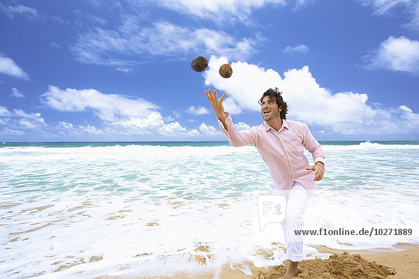'Man throwing coconuts on the beach; Kealia  Kauai  Hawaii  United States of America'