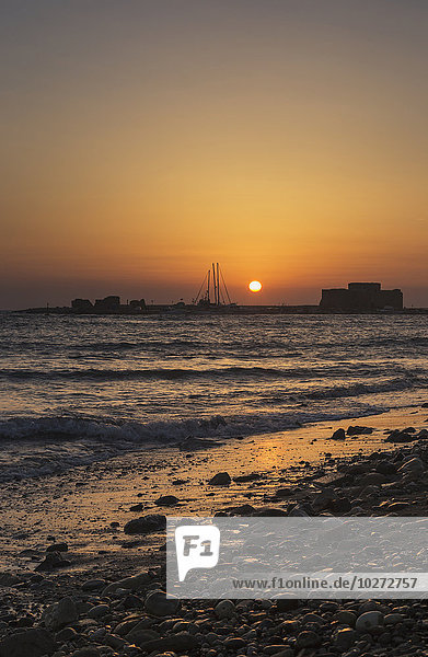 Glühender orange-gelber Himmel bei Sonnenuntergang über einer mediterranen Küste; Paphos  Zypern'.