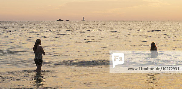 Schwimmen im Meer bei Sonnenuntergang mit Booten in der Ferne; Ixtapa-Zihuatanejo  Guerrero  Mexiko'.