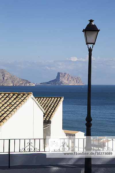 Laternenpfahl und Gebäude entlang der Küste mit einer zerklüfteten Küstenlinie in der Ferne; Altea  Spanien'.