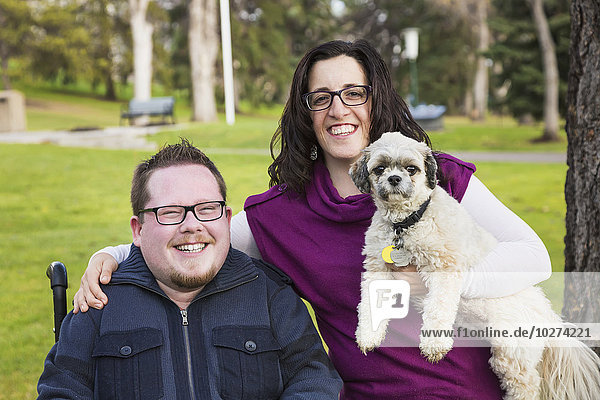 Behinderter Mann  seine Frau und ihr Hund posieren für ein Familienporträt in einem Park im Herbst; Edmonton  Alberta  Kanada'.