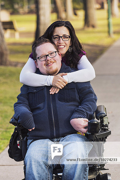 'Disabled husband with his wife posing for a picture in a park in autumn; Edmonton  Alberta  Canada'