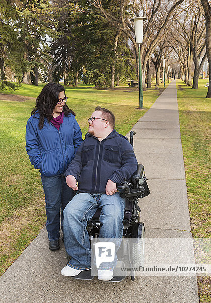 'Disabled husband talking with his wife while walking in a park in autumn; Edmonton  Alberta  Canada'