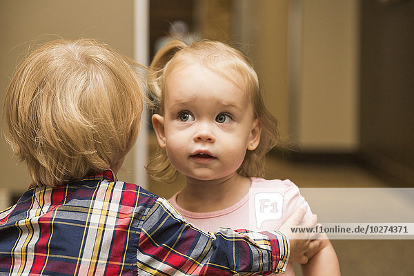 Zwei Kleinkinder umarmen sich im Flur einer zahnärztlichen Familienklinik; Edmonton  Alberta  Kanada'.