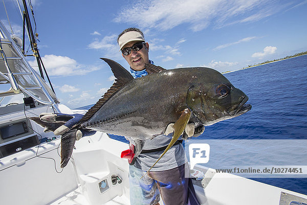 'Fisherman holds a fresh caught Jack Fish; Tahiti'
