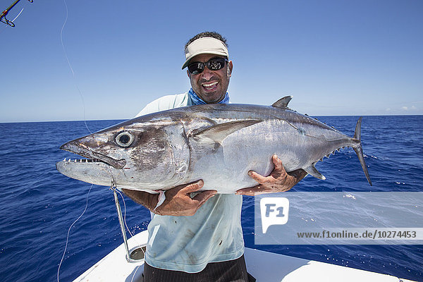 'Fisherman holding a fresh caught Dogtooth Tuna (Gymnosarda unicolor); Tahiti'