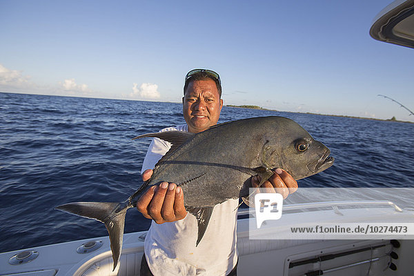 Fischer mit frisch gefangenem Jack-Fisch (Carangidae); Tahiti'.