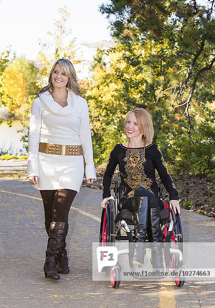 'Young paraplegic woman and her friend spending quality time together in a city park in autumn; Edmonton  Alberta  Canada'