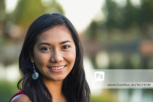 'Portrait of a beautiful young Filipino woman smiling in a city park in autumn; St. Albert  Alberta  Canada'