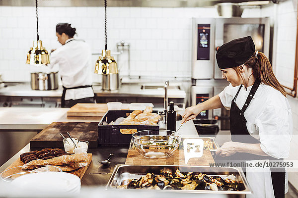 Female chef preparing food in commercial kitchen