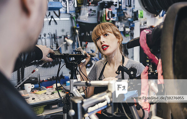 Female mechanic talking to customer in bicycle repair shop