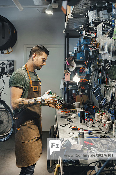 Mittlerer Erwachsener Mechaniker repariert Fahrradpedal in der Werkstatt
