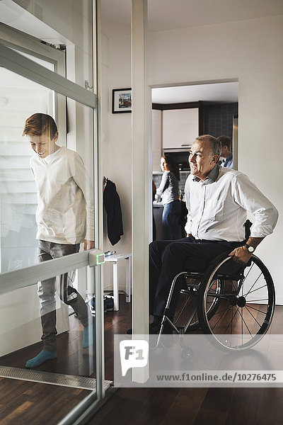 Sohn und Vater beim Betreten des Rollstuhlliftes zu Hause