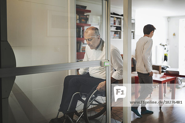 Behinderter Mann im Rollstuhl verlässt den Aufzug zu Hause
