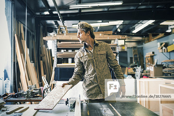 Carpenter looking away while working at table in workshop