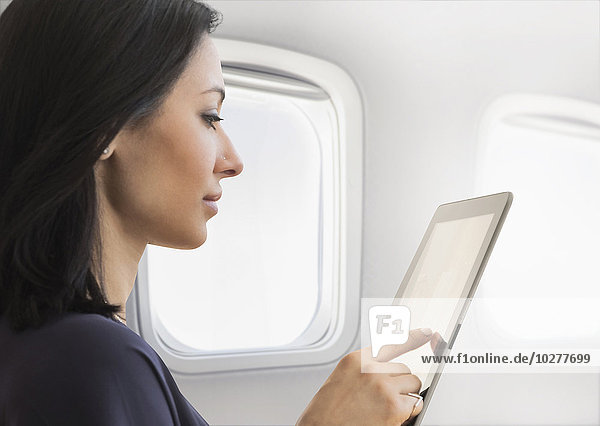 Junge Frau benutzt Tablet im Flugzeug