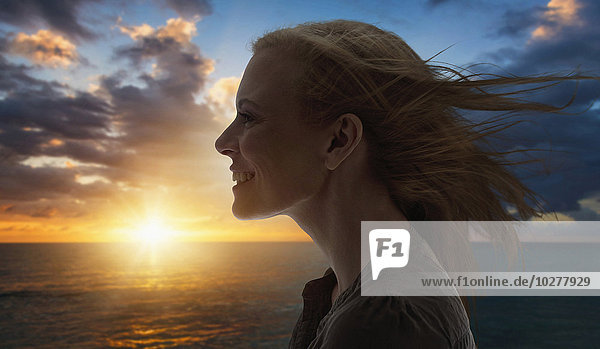 Portrait of woman by sea at sunset