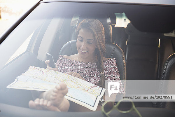 Frau sitzt im Auto und schaut auf die Karte