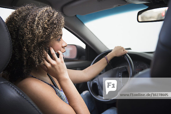 Junge Frau telefoniert beim Autofahren