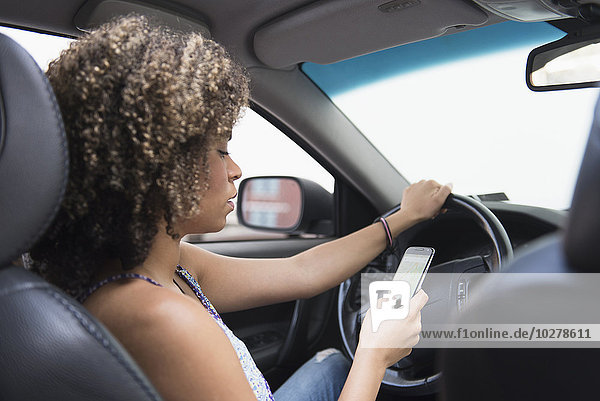 Junge Frau  die beim Autofahren eine SMS schreibt