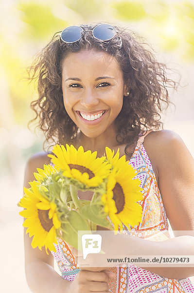 Portrait of smiling woman with sunflowers